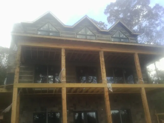 Dormers and porch framing on a large log home under construction — Roof Coating work by our crew in Hurst