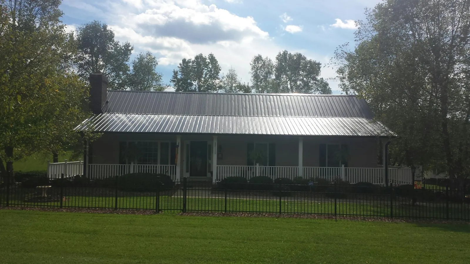 Gray metal roof on a brick ranch with a full width front porch — Gutter Guard Installation work by our crew in Hurst