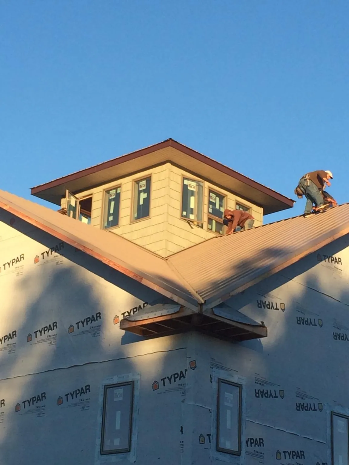 Roofers working around a rooftop cupola on a new metal roof at sunset — Roof Waterproofing in Hurst by Roofing Brothers